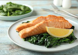 Cooked salmon with spinach and lemon on wooden table, closeup. These are all foods that can combat dry eye symptoms!