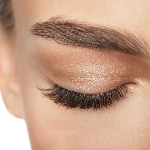 Close-up photo of a model wearing eye makeup closed eyes and long eyelashes.